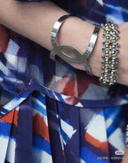 Silver-tone cuff bracelet with ornate charm detail on wrist