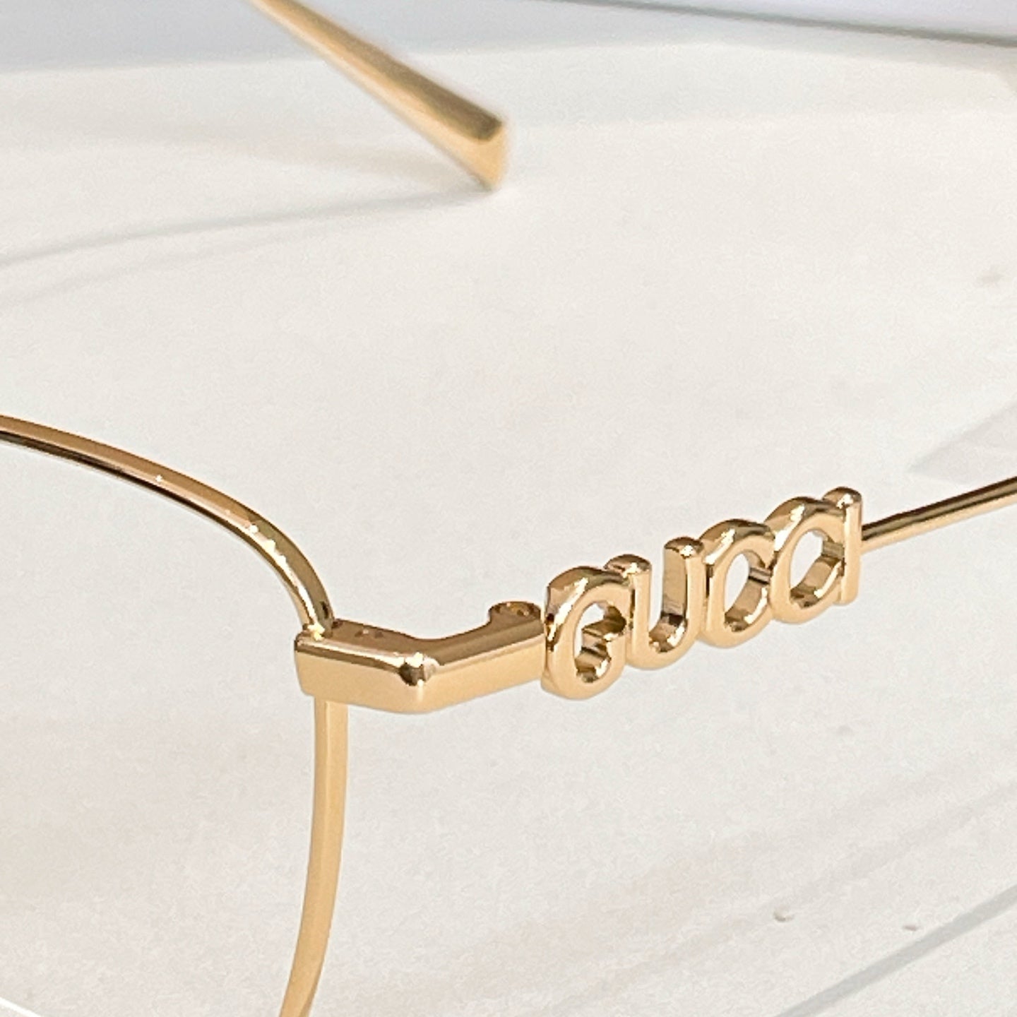Gucci eyeglass temple with gold metal 'Gucci' lettering detail.