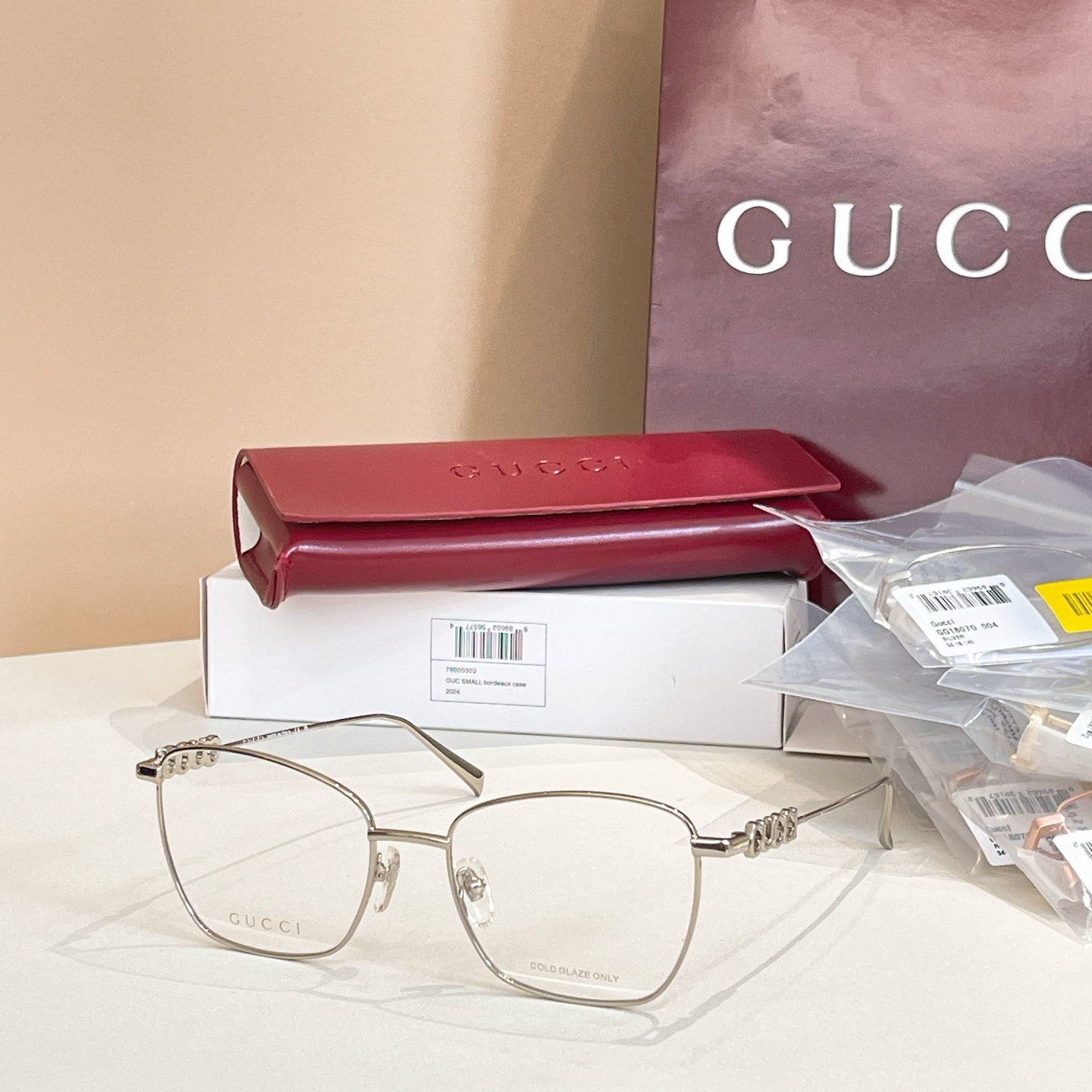 Gucci eyeglass frames with light gold metal temples and clear oval lenses.