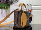 Monogram tote bag with tan leather handles and shoulder strap, side view