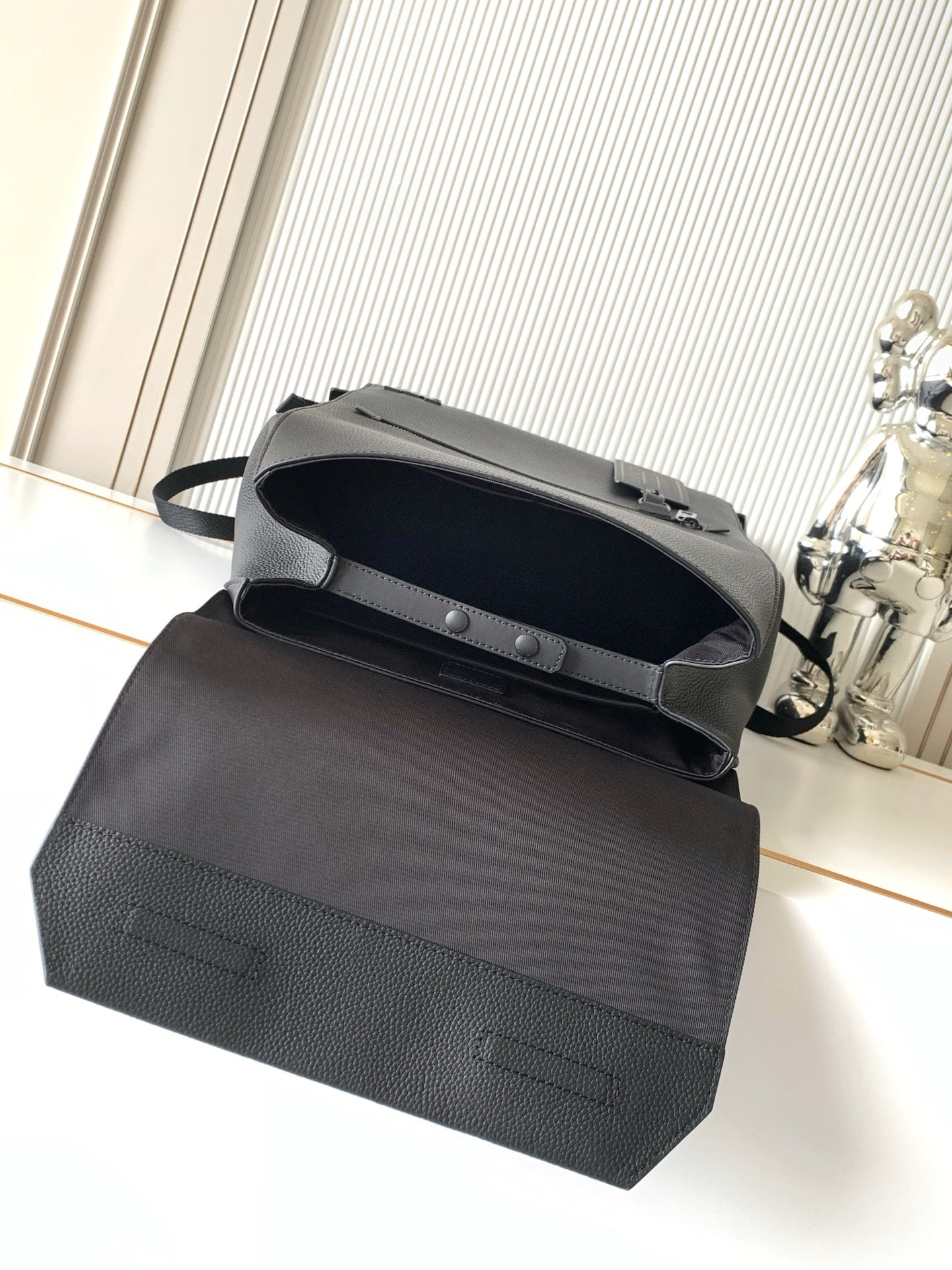 Men's Louis Vuitton bag top view with snap flap and short handle, dark leather-look.