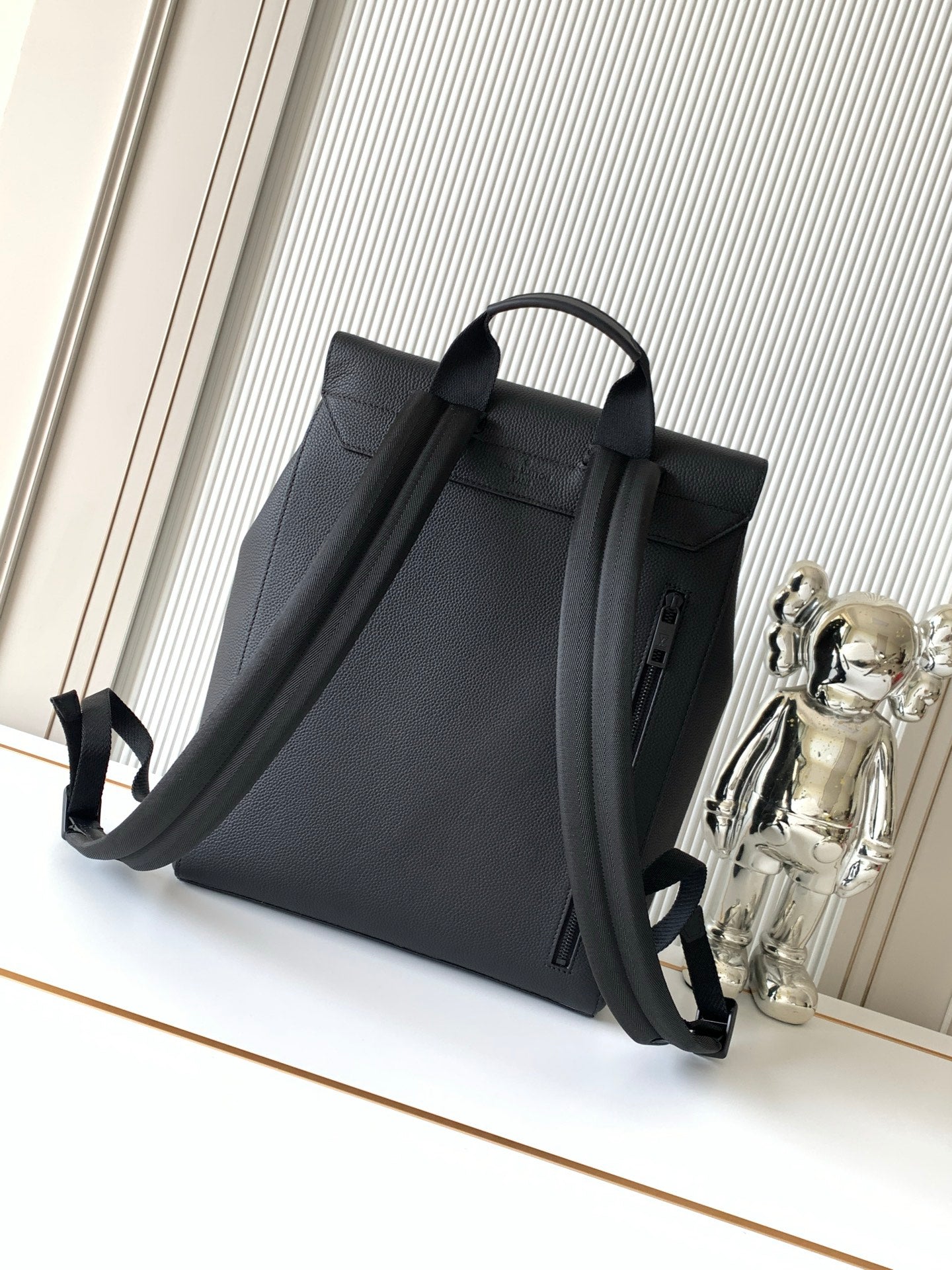 Men's Louis Vuitton bag from side angle, top handle and adjustable shoulder strap, dark.