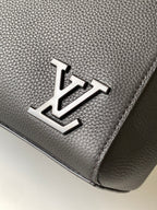 Men's Louis Vuitton bag close-up of metal logo on dark grained leather-look.