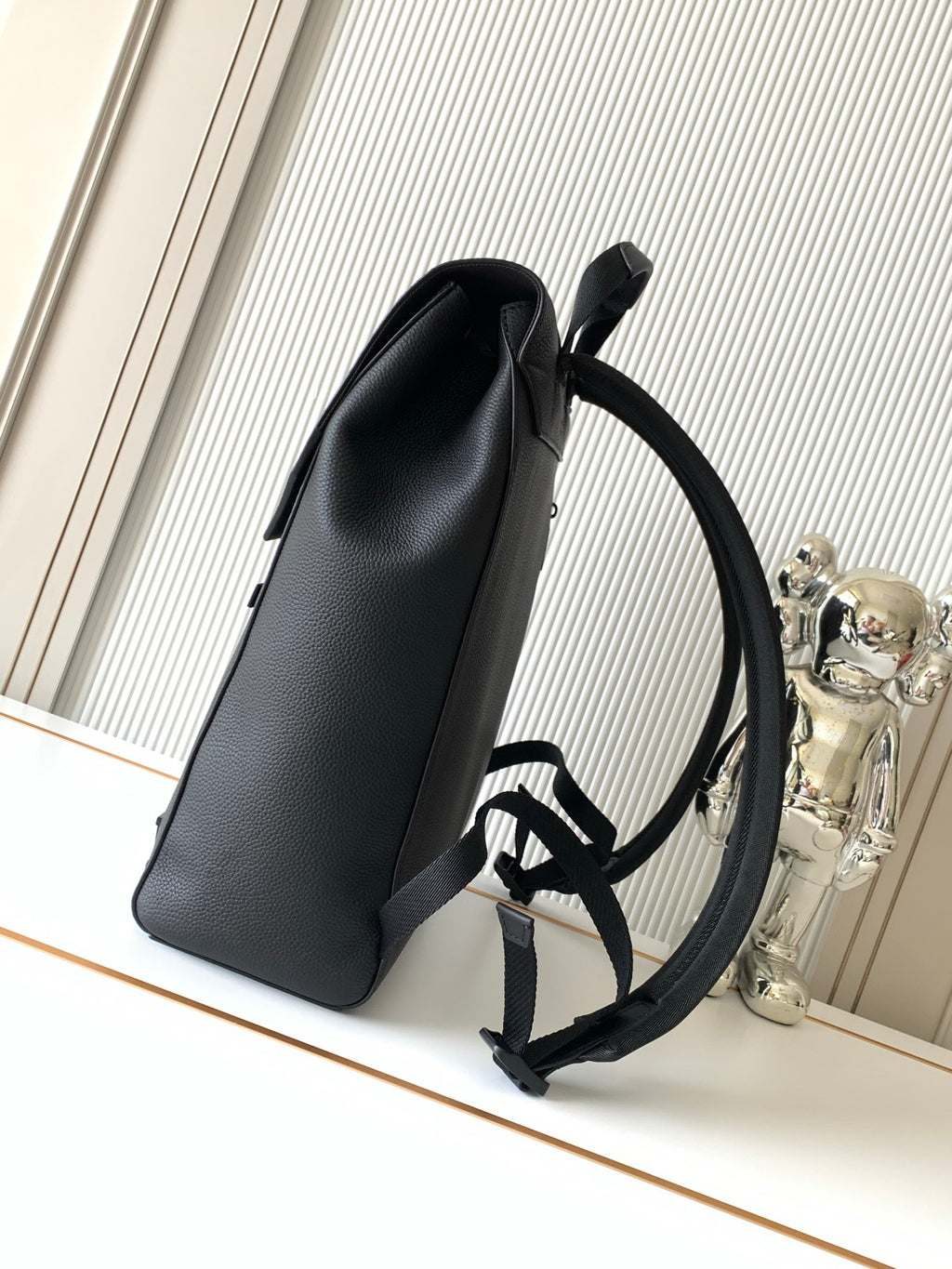 Men's Louis Vuitton bag upright view with top handle and wide shoulder strap, dark.