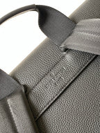 Men's Louis Vuitton bag close-up of strap attachment and textured leather detail, dark.