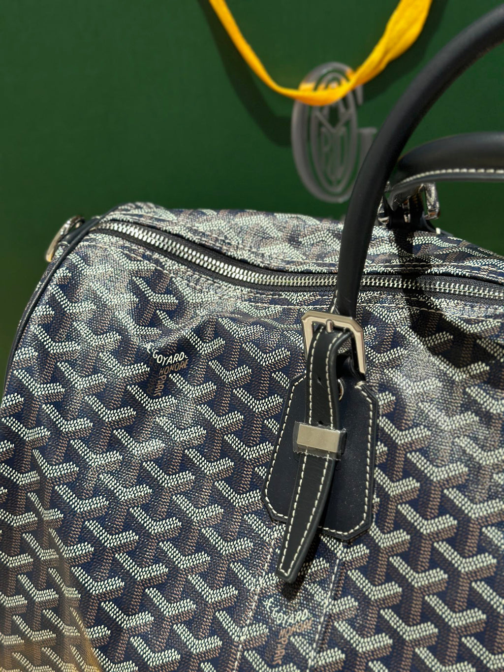 Goyard duffel bag close-up with textured navy patterned canvas and small front strap details