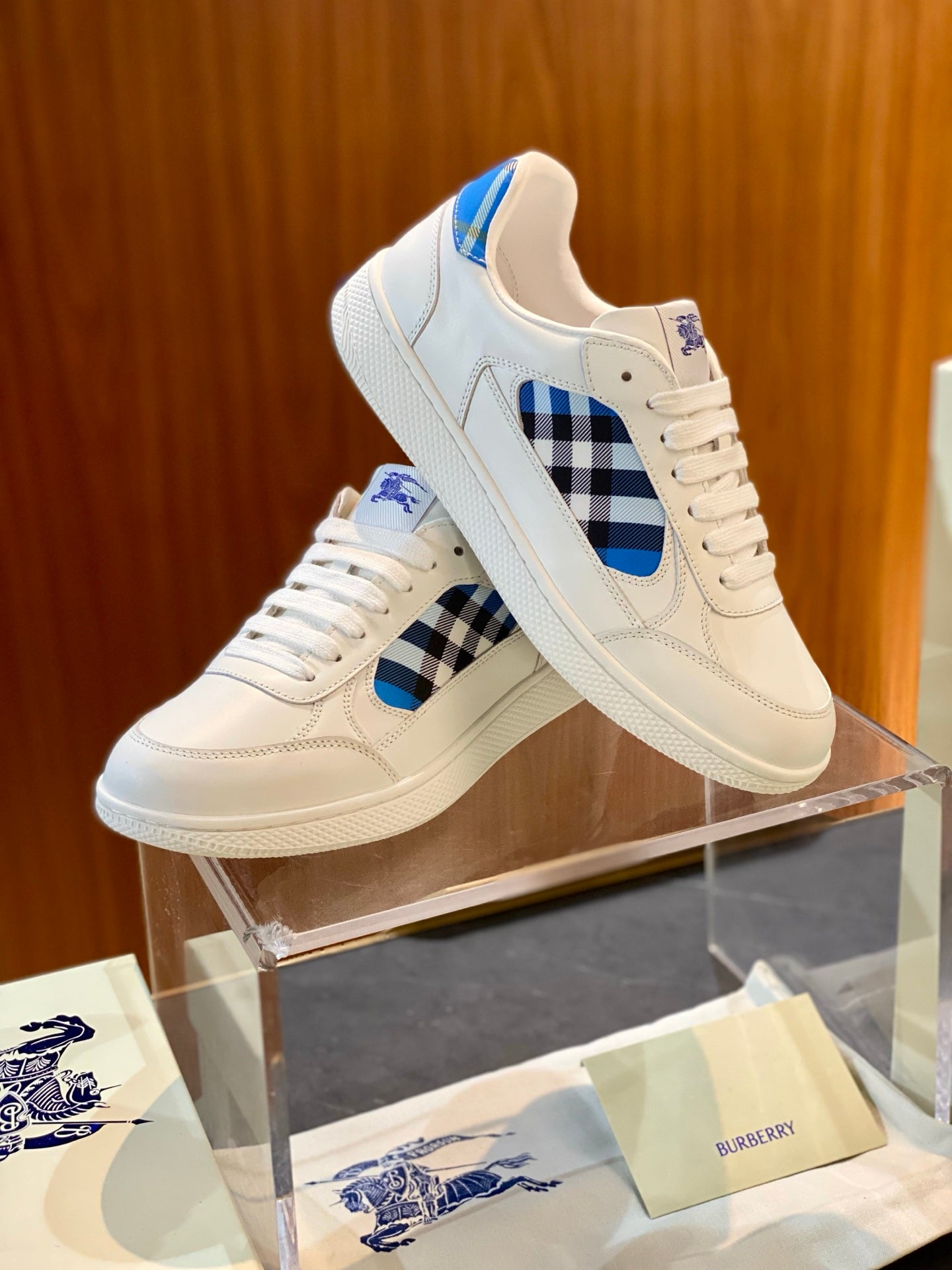 Pair of white low-top sneakers with blue check accent on side and lace-up uppers