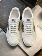 White leather sneakers with blue crest tongue, lace-up front and clean toe shape