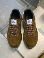 Brown suede lace-up sneakers with blue logo patch at the tongue