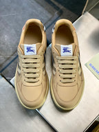 Cream/beige sneakers viewed from front, lace-up with blue logo patch on tongue