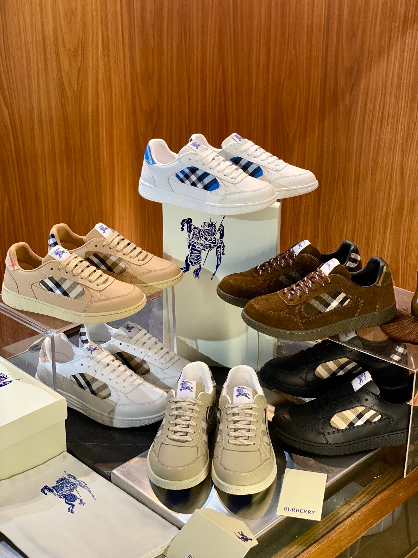 Assorted Burberry-style sneakers on display: white, beige, and brown low-top pairs