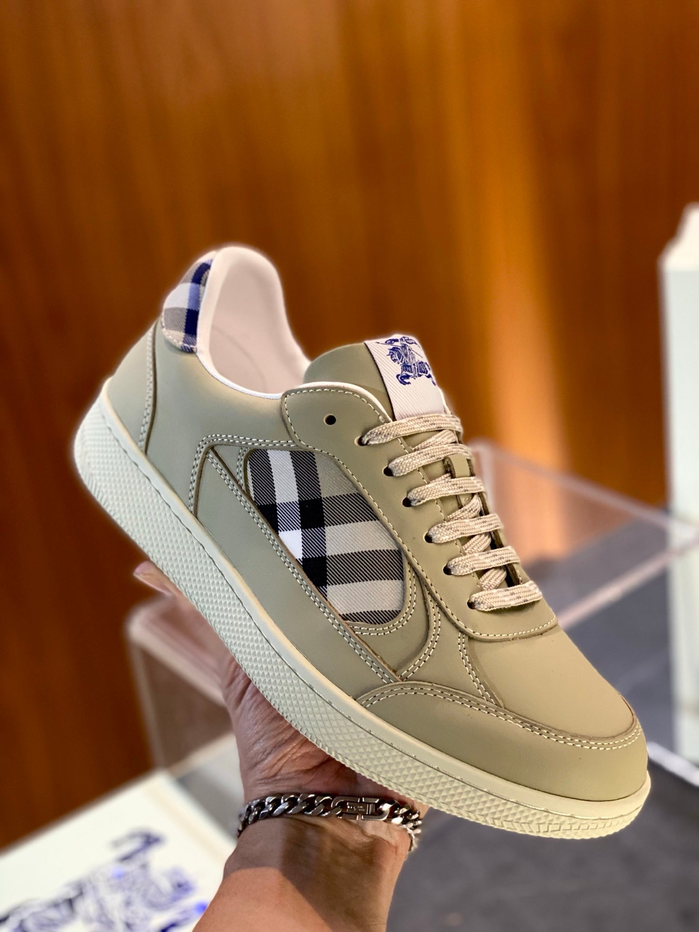 Beige low-top sneaker on clear display with plaid side panel and lace-up