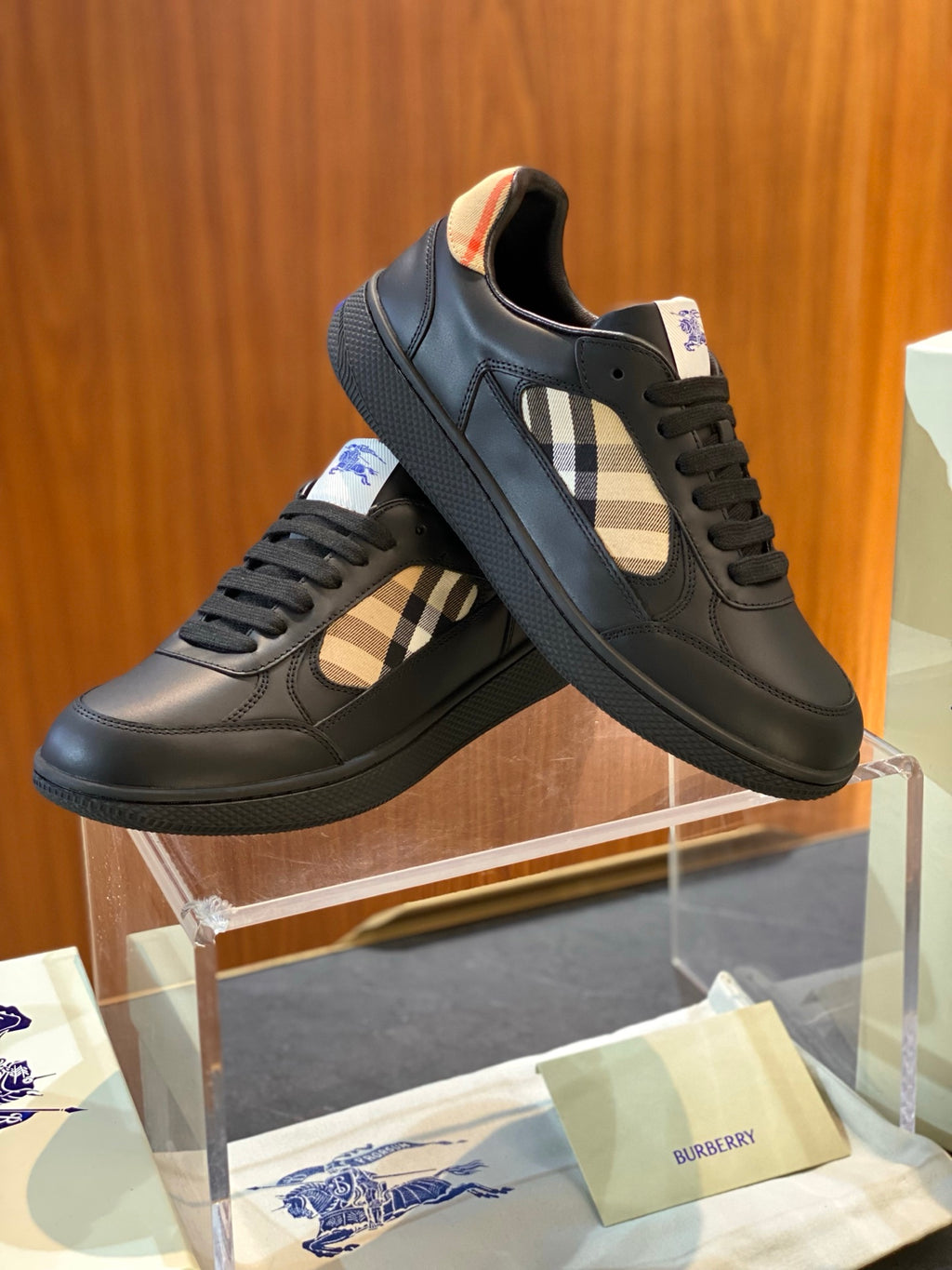 Dark leather low-top sneakers with plaid side panel and lace-up, angled view