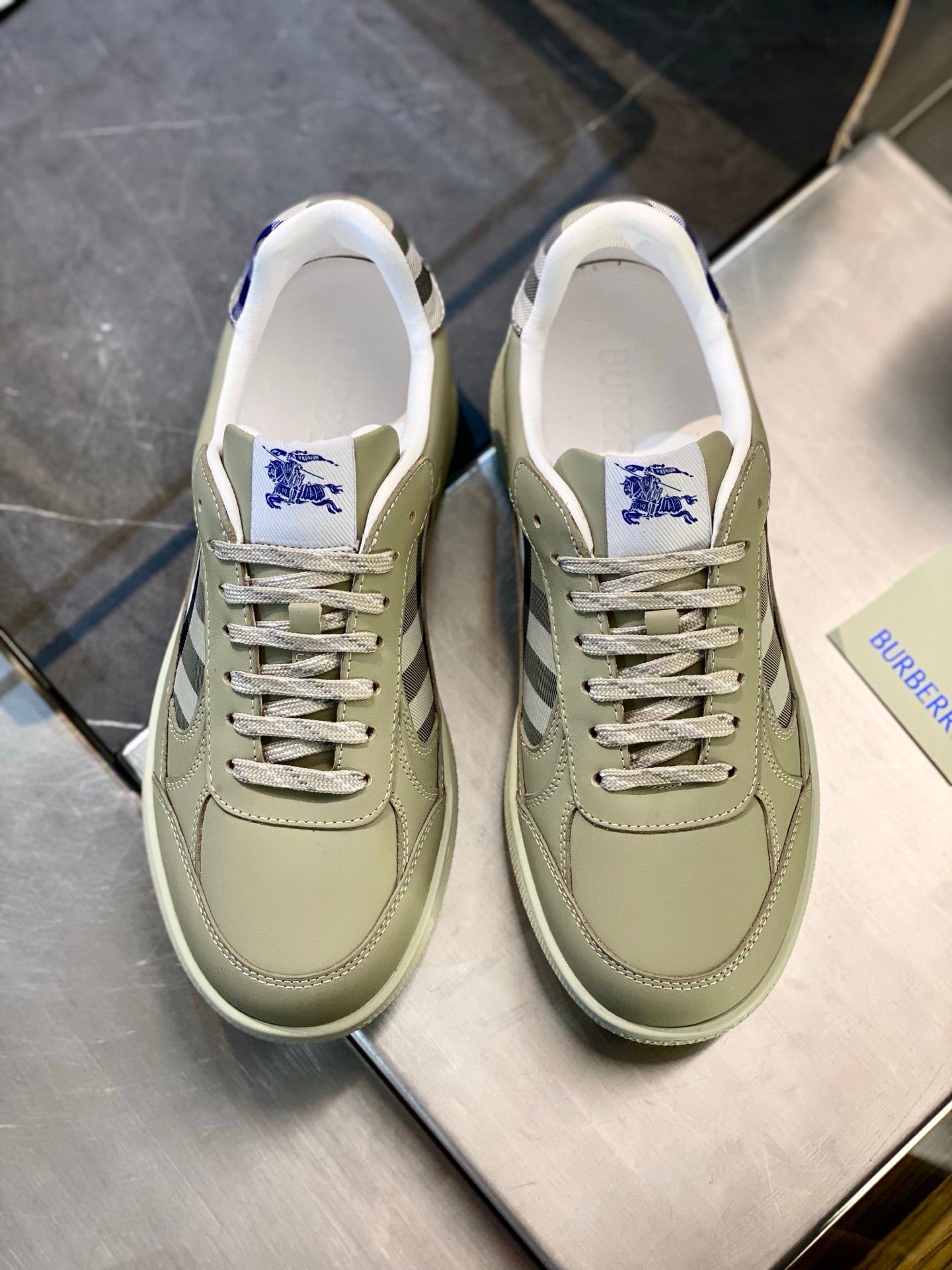 Pair of light beige leather sneakers with plaid logo and lace-up, front view