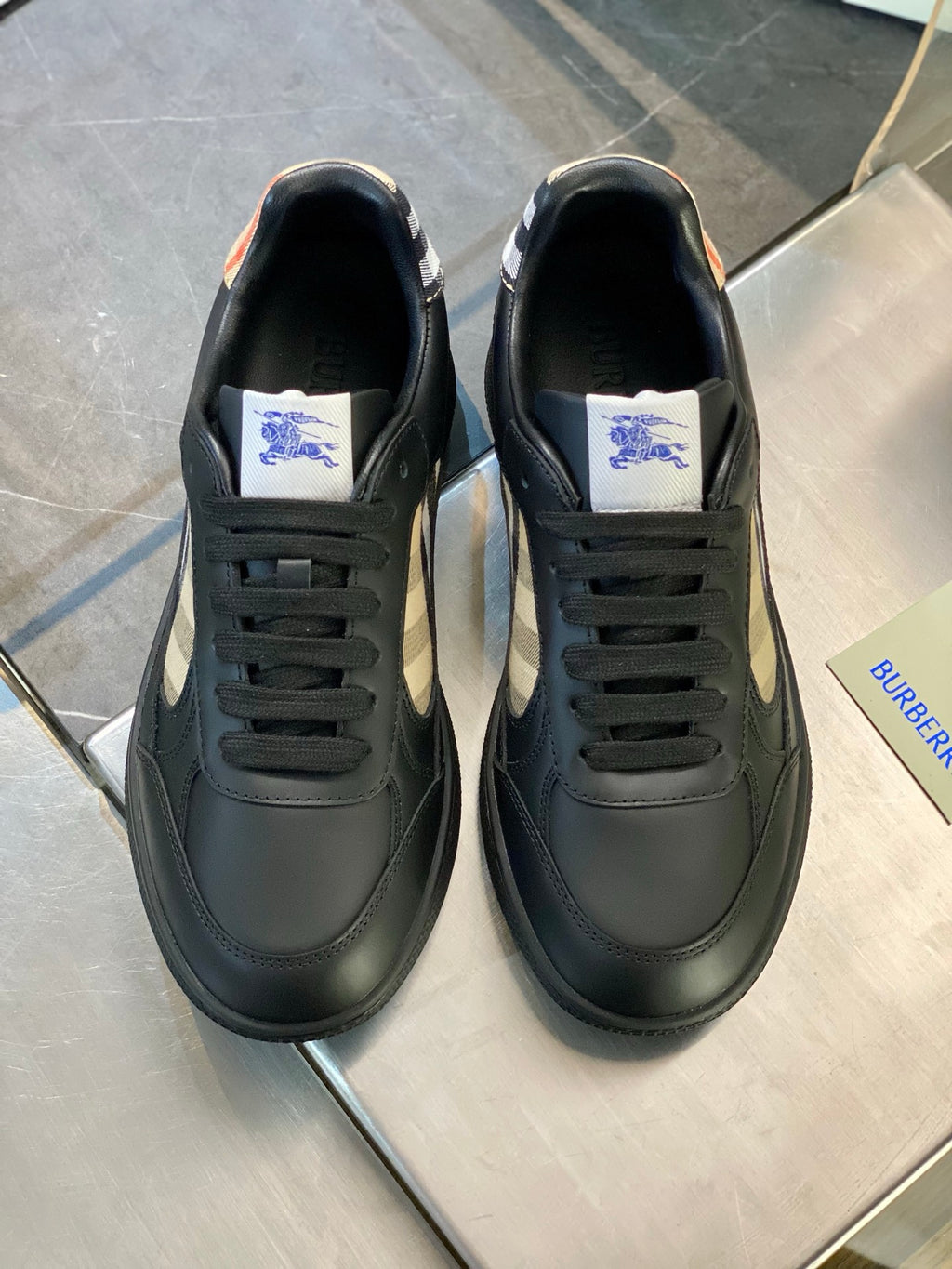 Black leather sneakers with plaid logo on sides and blue horse logo on tongue
