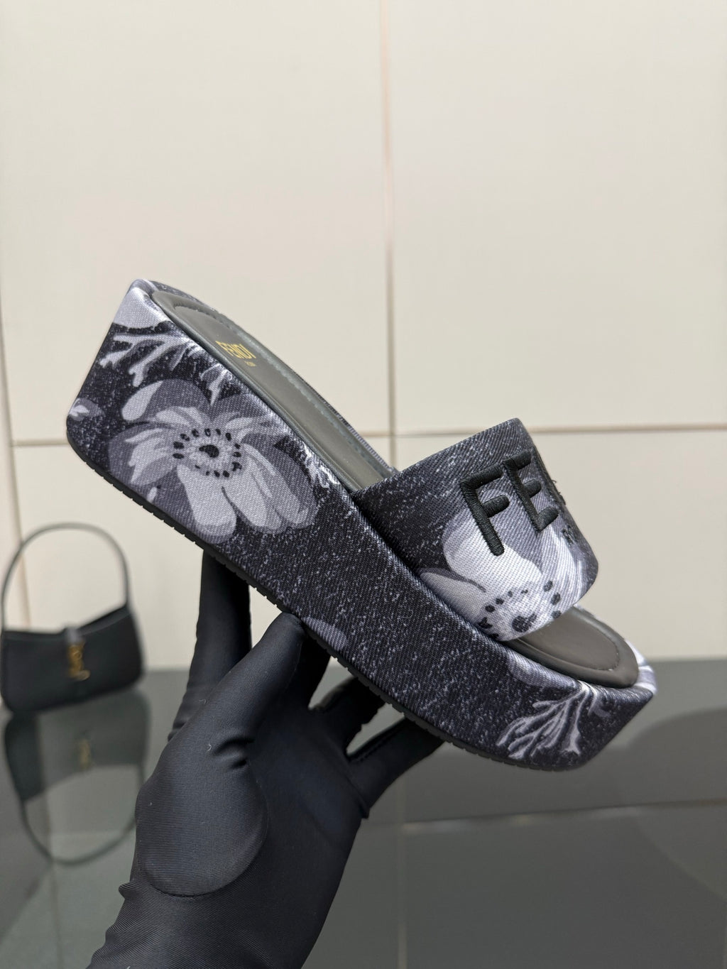 Fendi single slide sandal close-up, dark floral strap with FF logo detail.