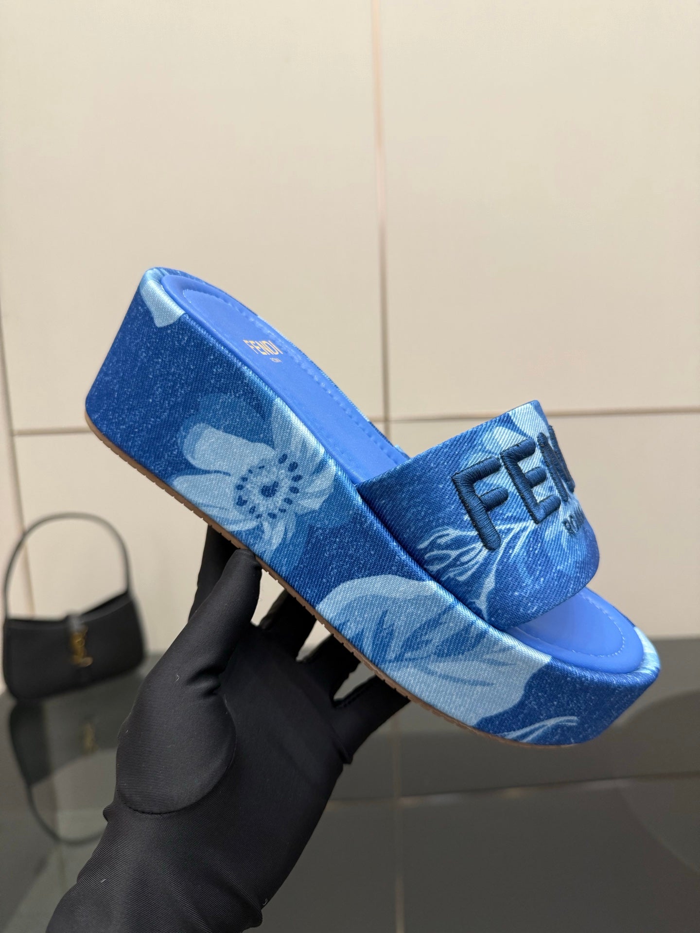 Fendi women's blue slide sandal, close-up of FF logo strap and patterned upper.