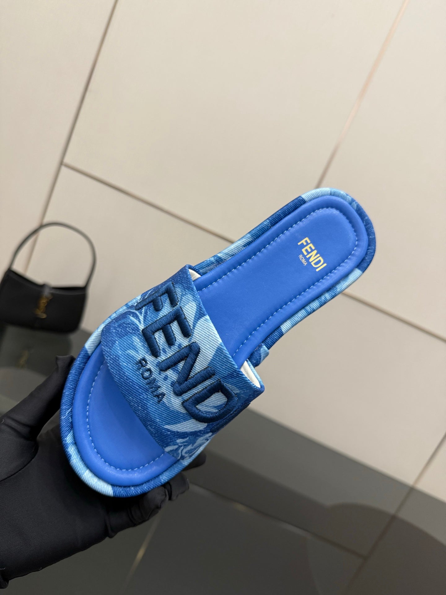 Fendi women's blue slide sandal close-up, FF logo on strap over blue footbed.