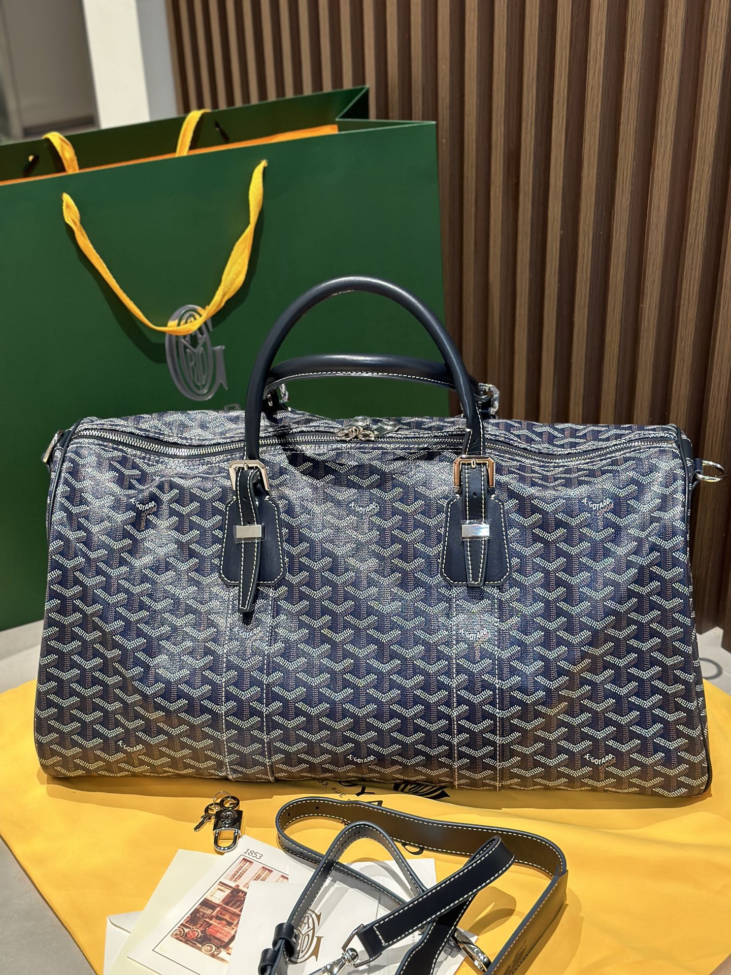 Goyard duffel bag with navy patterned canvas, leather handles, and front zip pockets