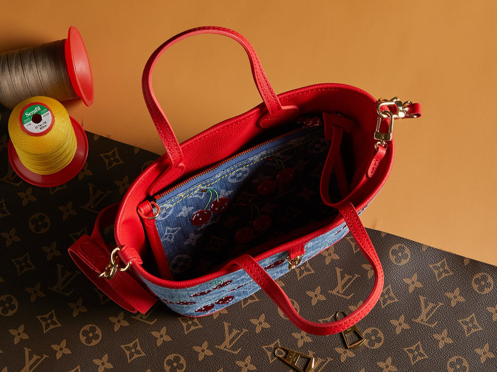 Denim tote bag with red handles, open top showing interior and zip pocket