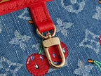 Gold clasp with cherry charm on red strap over denim