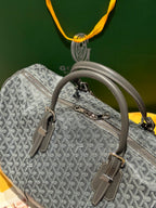 Grey patterned duffel bag with top handle, side buckles, and zip front