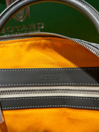 Duﬀel bag top zipper with orange lining and embossed maker mark on leather