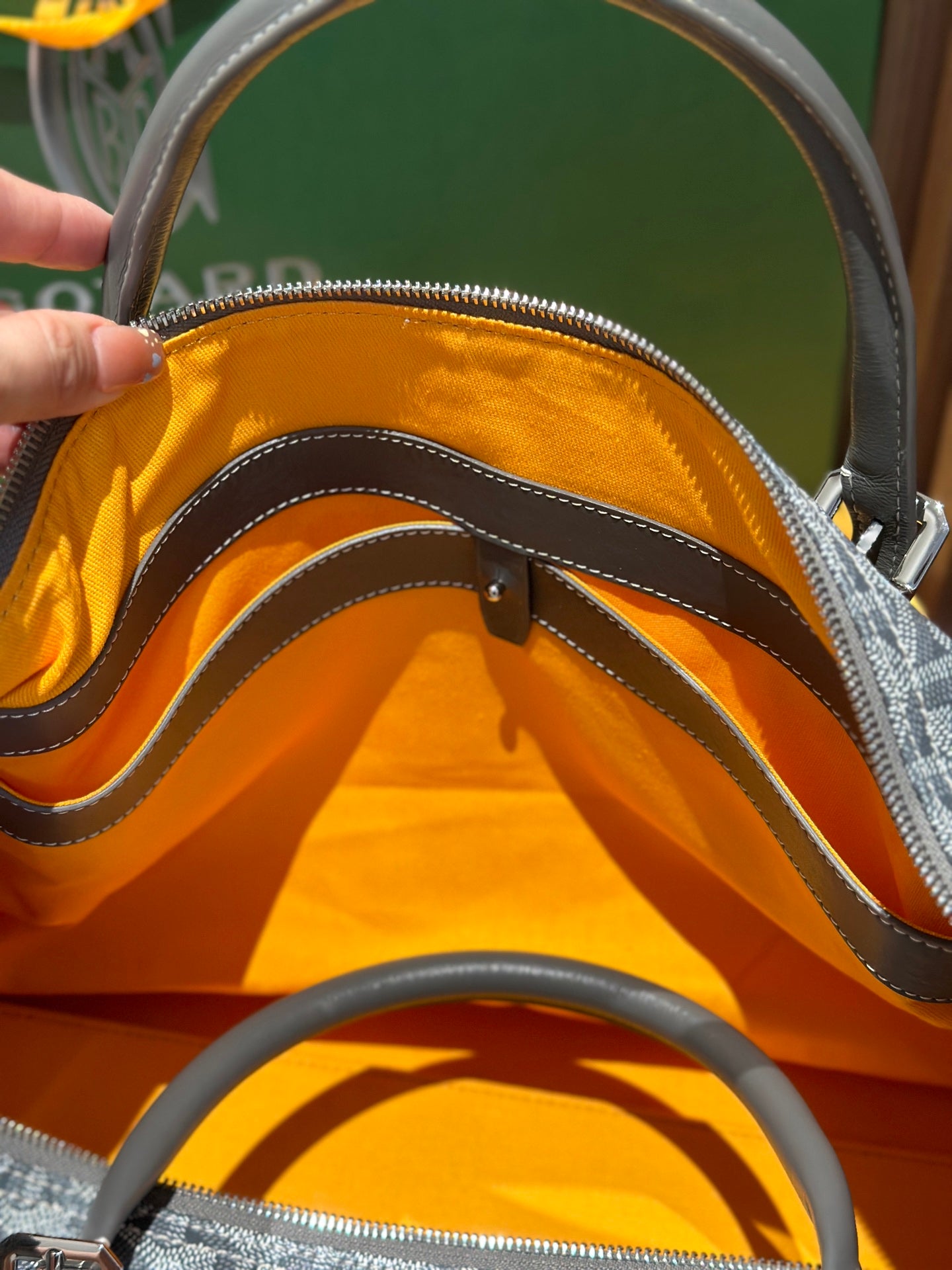 Duﬀel bag opening with orange lining and stitched handles, zip edge