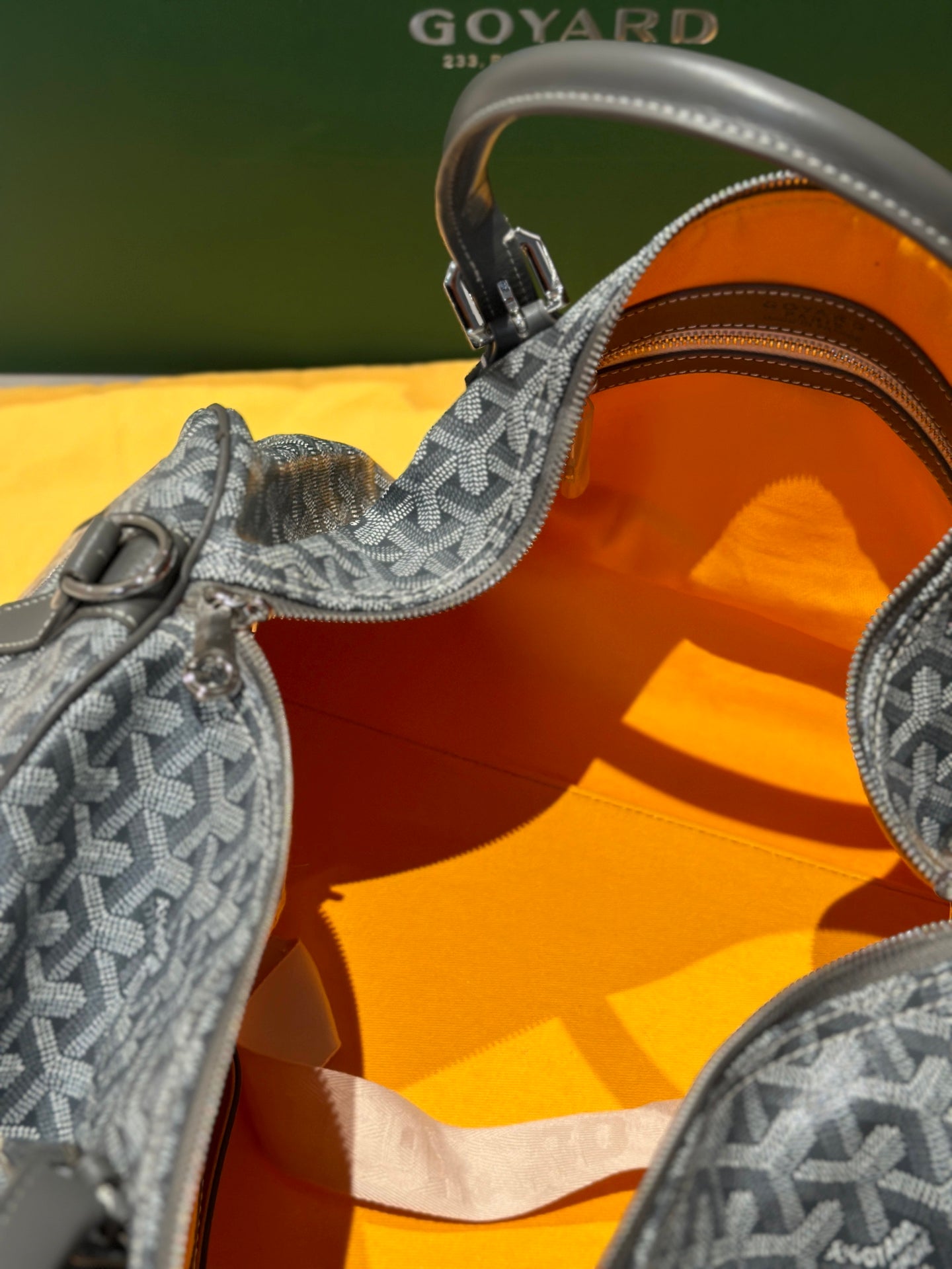 Duffel bag interior with orange lining and grey patterned trim near zipper