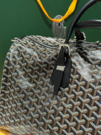 Goyard patterned travel bag close-up with front zipper and black leather strap tab