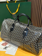 Goyard patterned travel bag front view with black handles and leather accent strap
