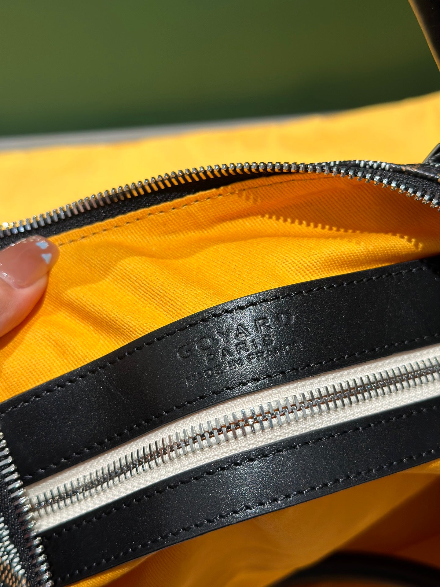 Goyard patterned travel bag close-up of zipper track and black leather trim