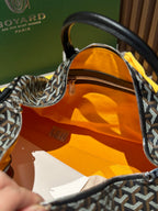 Goyard patterned travel bag open view showing orange fabric lining and zip pocket
