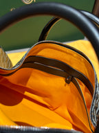 Goyard patterned travel bag interior view with orange lining and zip closure
