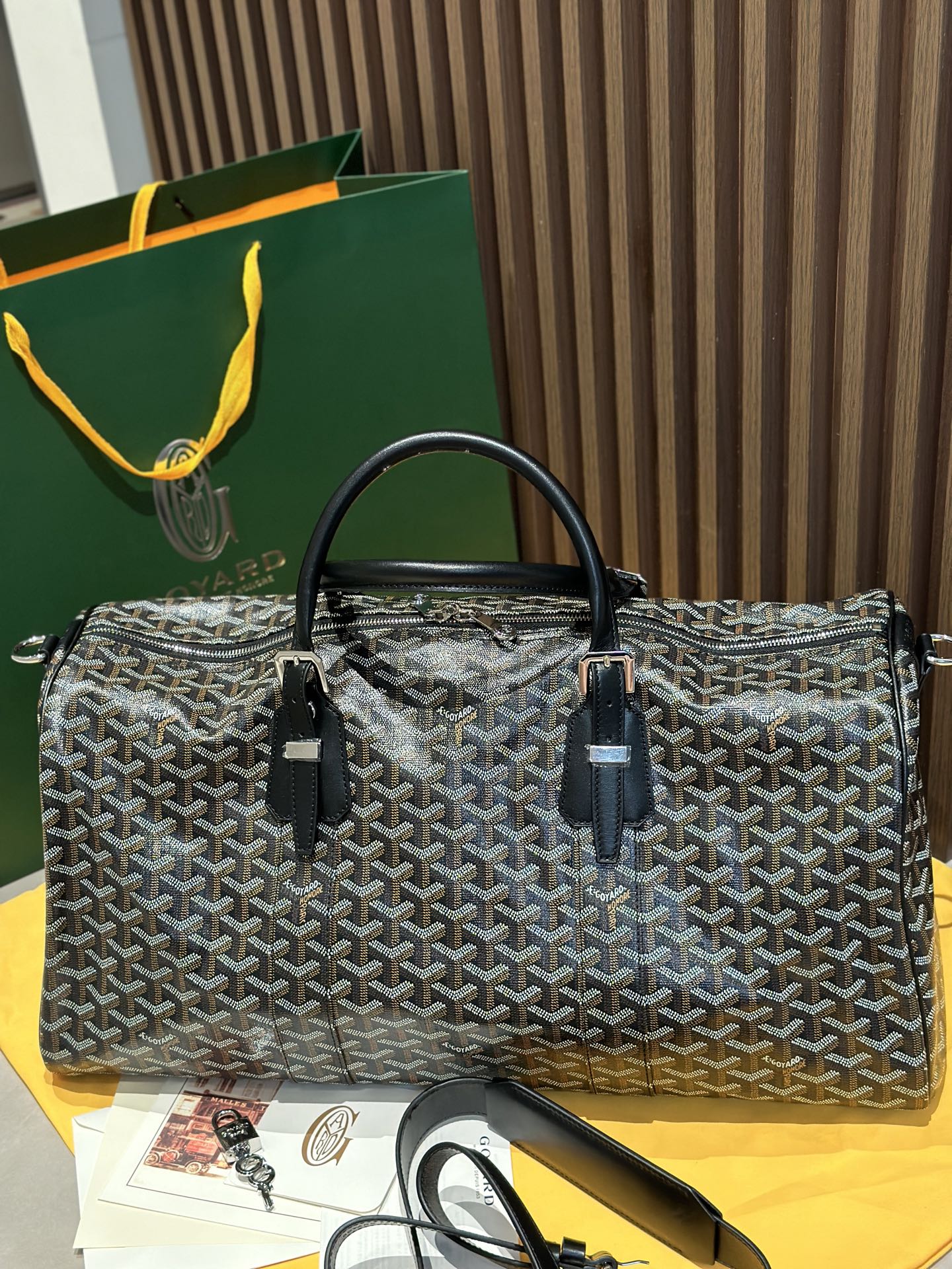Goyard patterned travel bag with black top handles and side leather trim