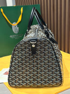 Goyard patterned travel bag with structured body, black handles, and hanging key charm