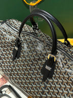 Goyard patterned travel bag angled view with black zipper pocket and top handles