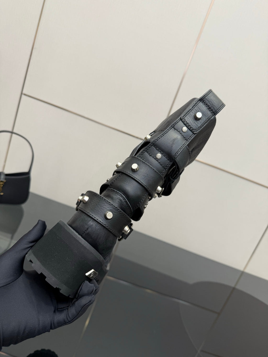 Black ankle boots with stacked straps and metal studs, shown from side