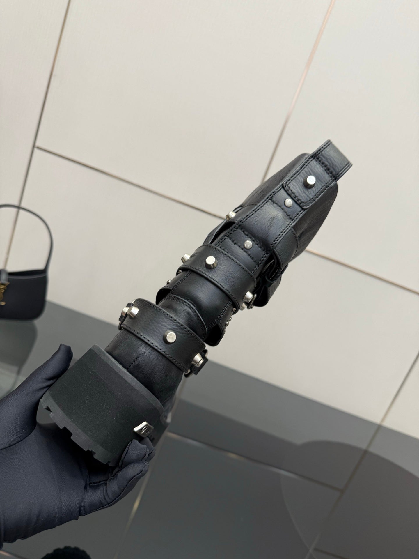 Black ankle boots with stacked straps and metal studs, shown from side