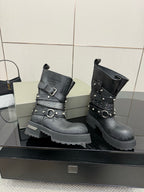 Black ankle boots with wide strap and metal buckle details, pair on display