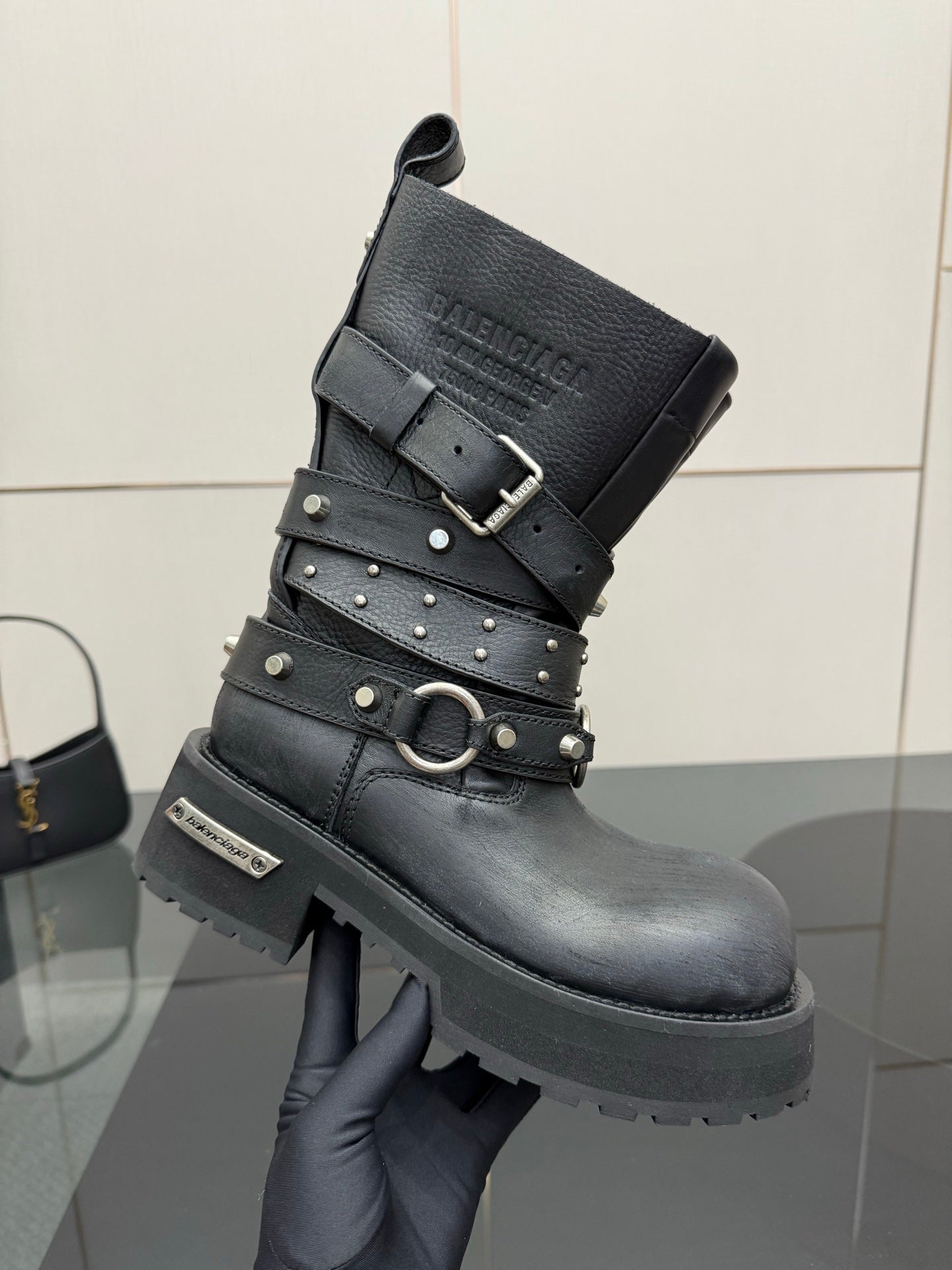 Black leather ankle boot with studded straps, square buckle, and thick sole