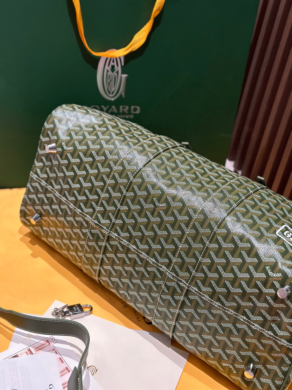Goyard duffel bag laid flat in sage-green Goyardine with silver zipper and strap accents