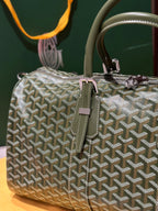 Goyard duffel bag with sage-green Goyardine pattern, green trim, and front buckle tabs