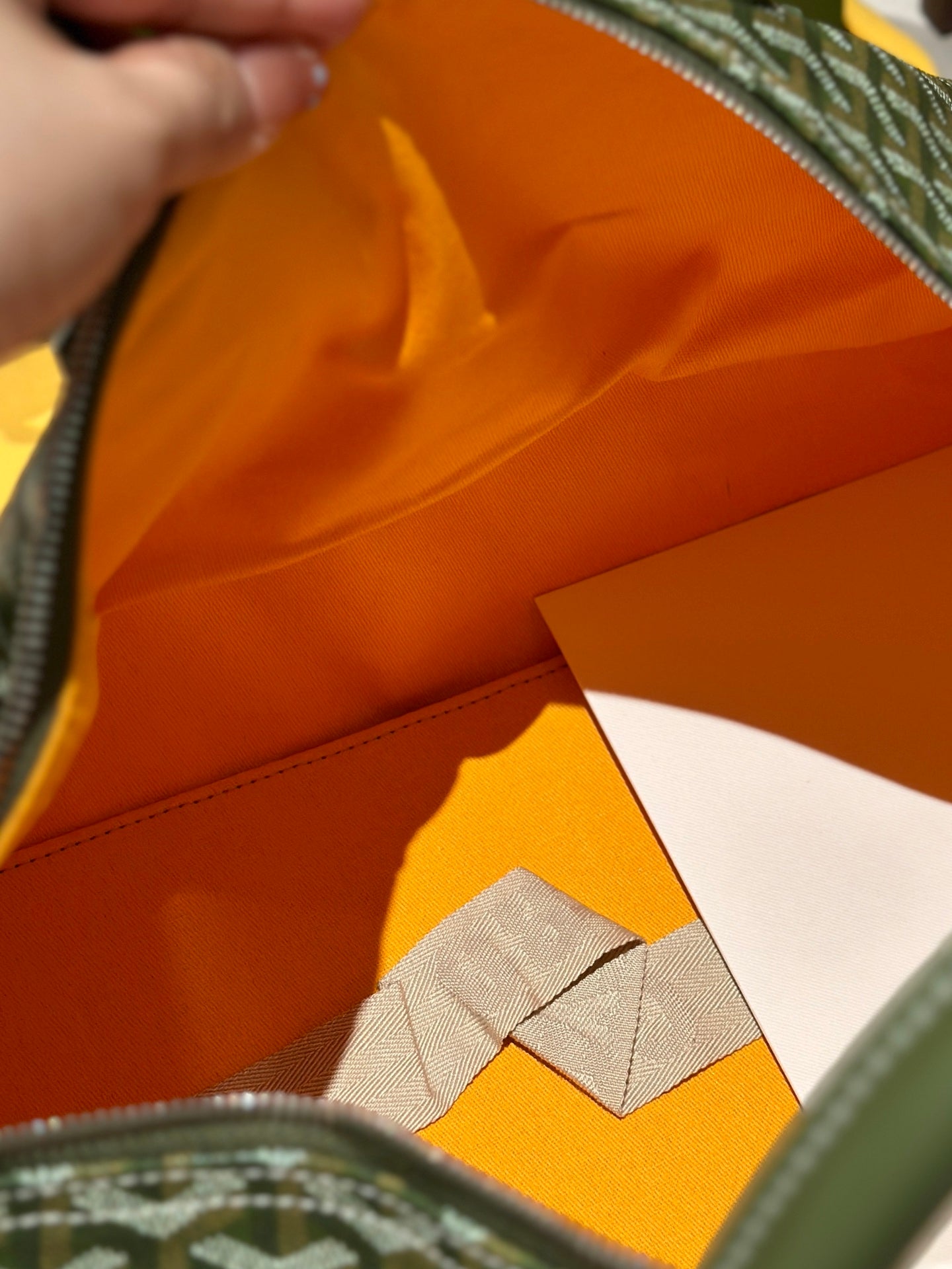 Duffel bag interior with orange lining and stitched seam along the zipper opening