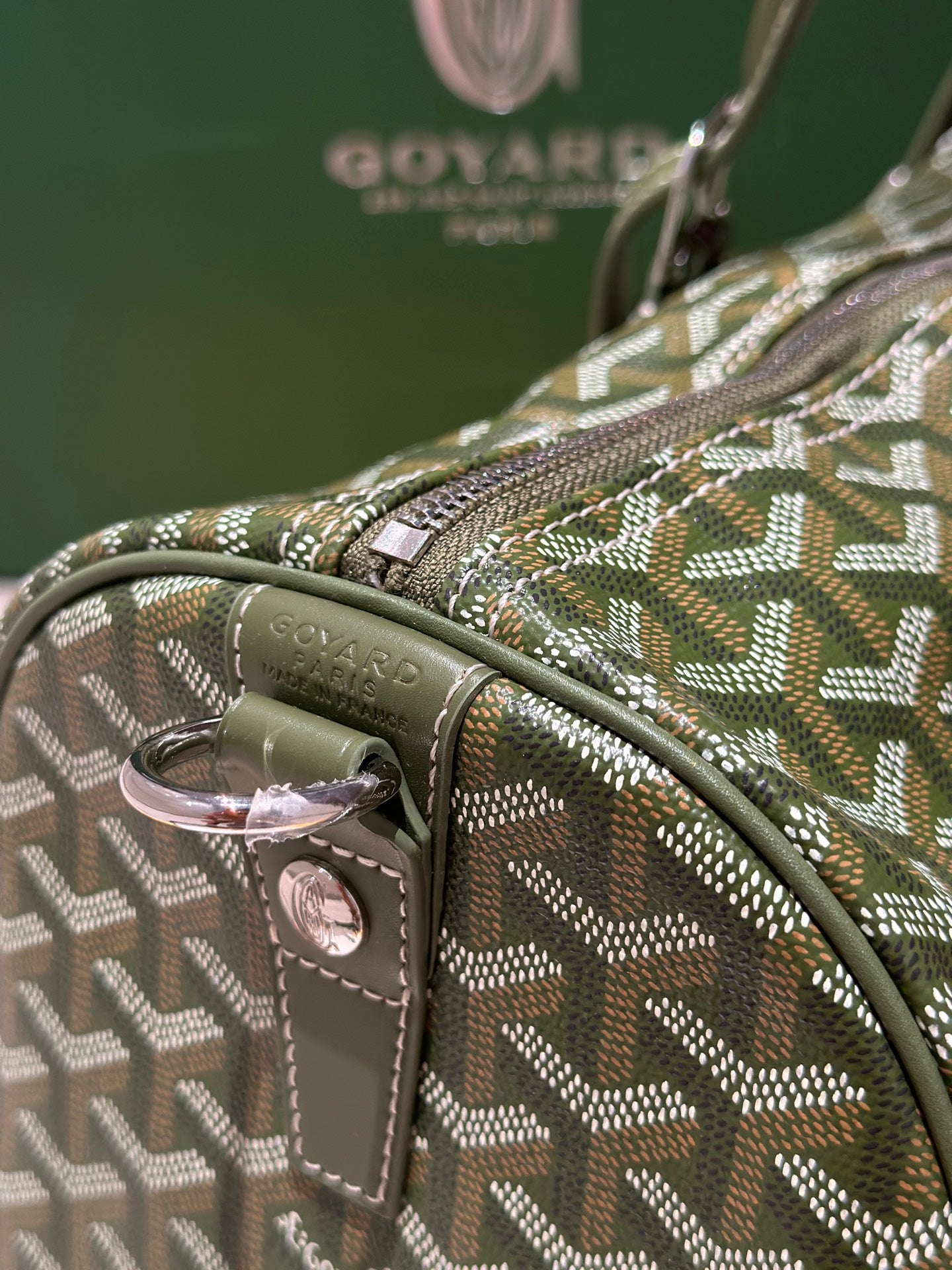 Goyard duffel bag side handle and leather strap with pink-toned buckle hardware