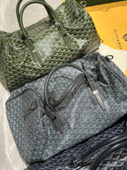 Stacked duffel bags in sage-green and dark-gray Goyardine with rolled top handles