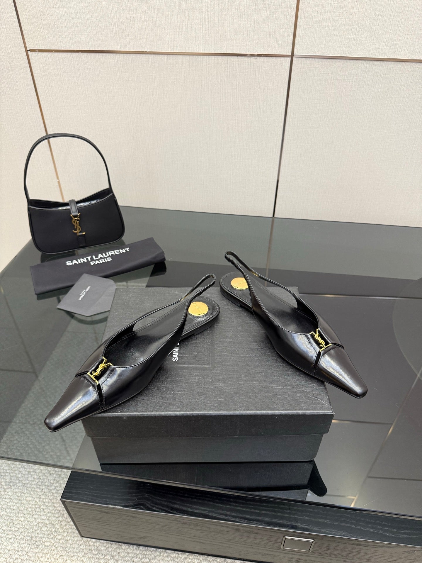 Black pointed-toe slingback heels with gold hardware, angled pair view