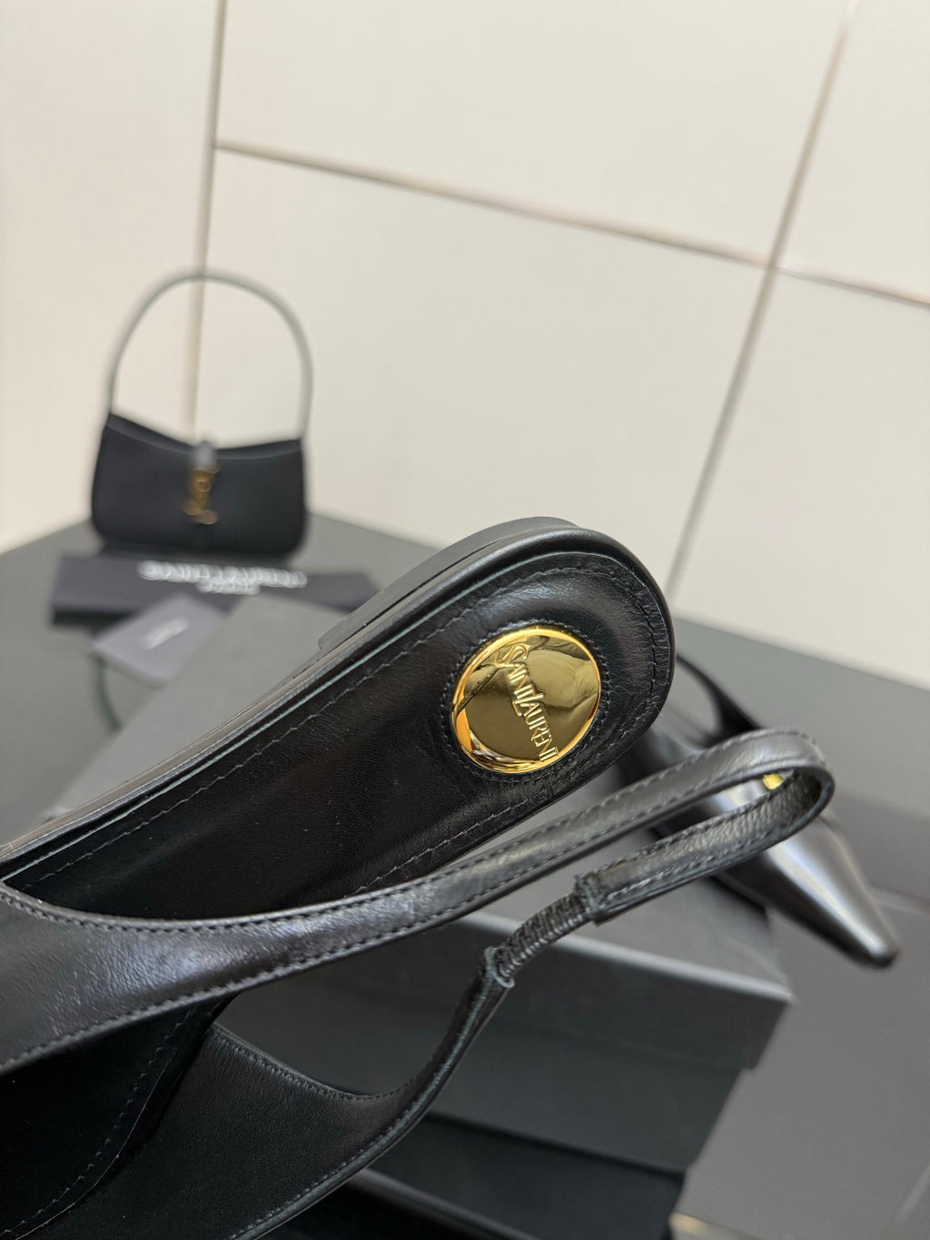 Black slingback heel close-up with gold emblem on toe