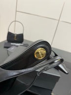 Black slingback heel close-up with gold emblem on toe