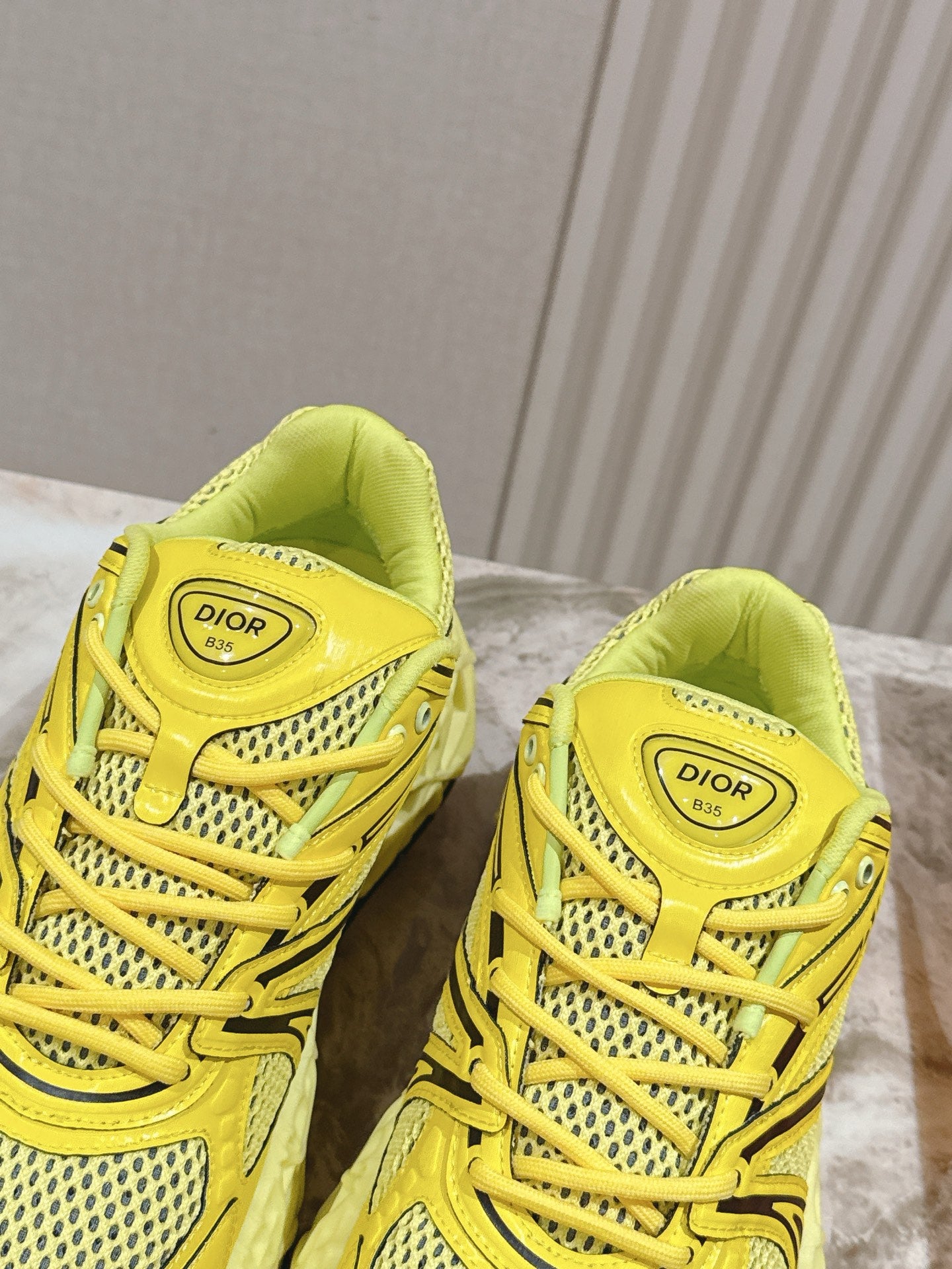 Dior unisex yellow sneakers with molded straps, mesh upper, and cushioned heel